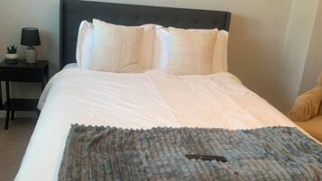 A neatly made bed with a blue blanket, a dark headboard, and two wall-mounted decorative panels.