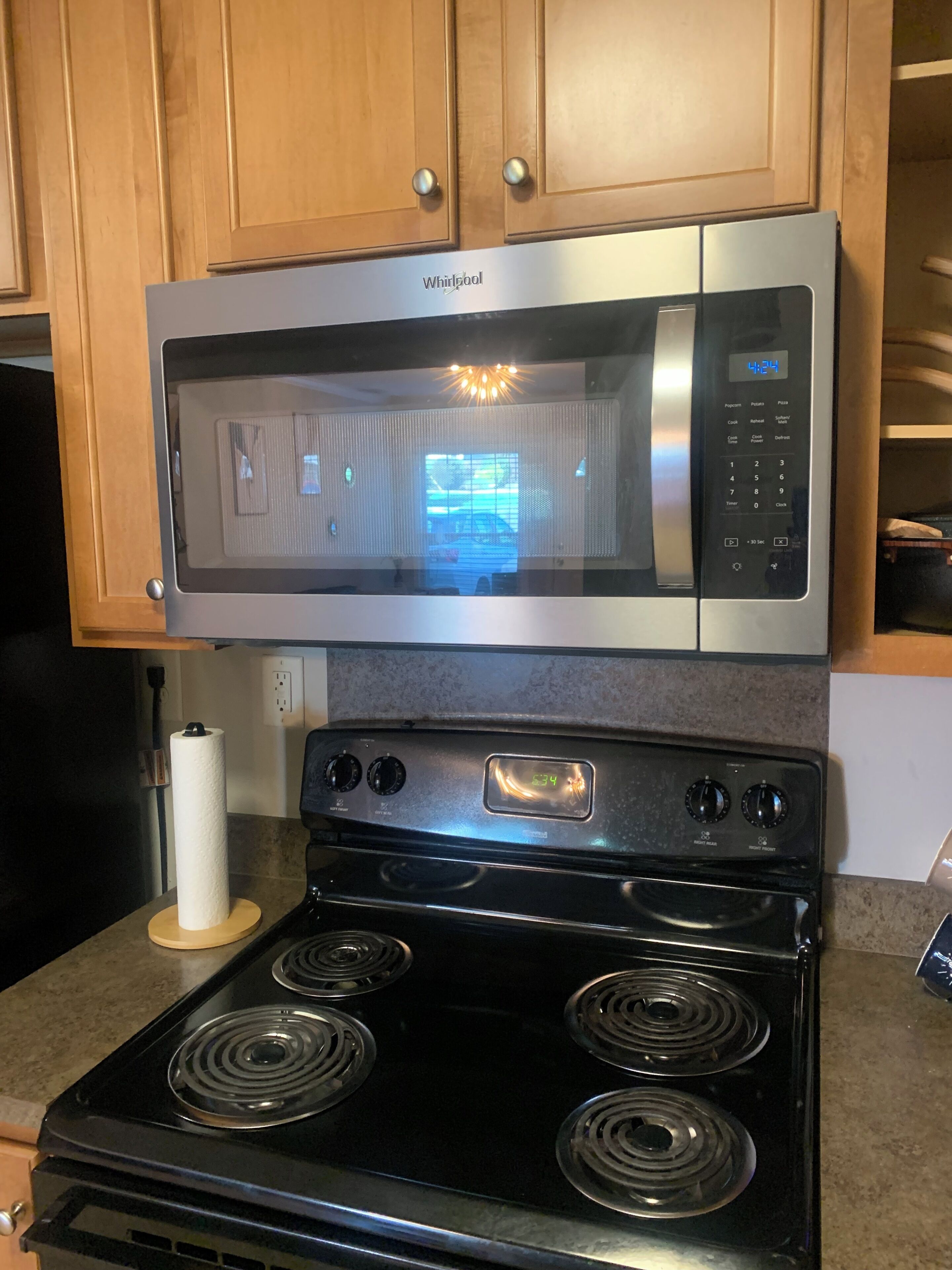 A kitchen with a stainless steel microwave and a black stove.