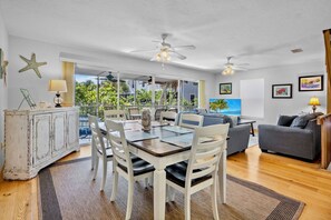 A dining area with a table and chairs, a ceiling fan, and a view of the outdoors. - Sunshine Daydream in Anna Maria Island (Holmes Beach)