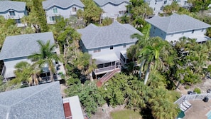 A residential area with multiple two-story houses, each with a covered porch and surrounded by various trees and vegetation. - Sunshine Daydream in Anna Maria Island (Holmes Beach)