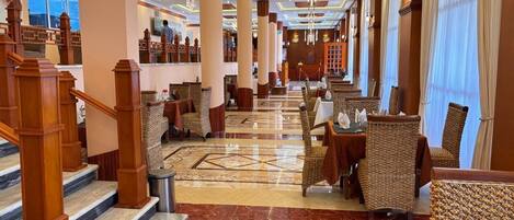 Een hotellobby met een statige trap, hoge plafonds en diverse zithoeken.
