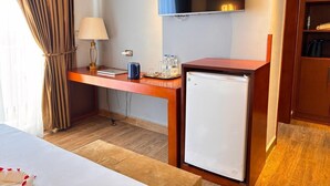 A hotel room with a bed, a desk with a lamp, a television, and a mini-fridge. - 2RN Solomon Hotel (Sendafa)