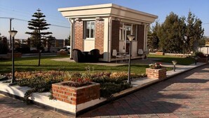 A small brick building with a flat roof, a covered porch, and a landscaped garden with flowers and shrubs. - 2RN Solomon Hotel (Sendafa)