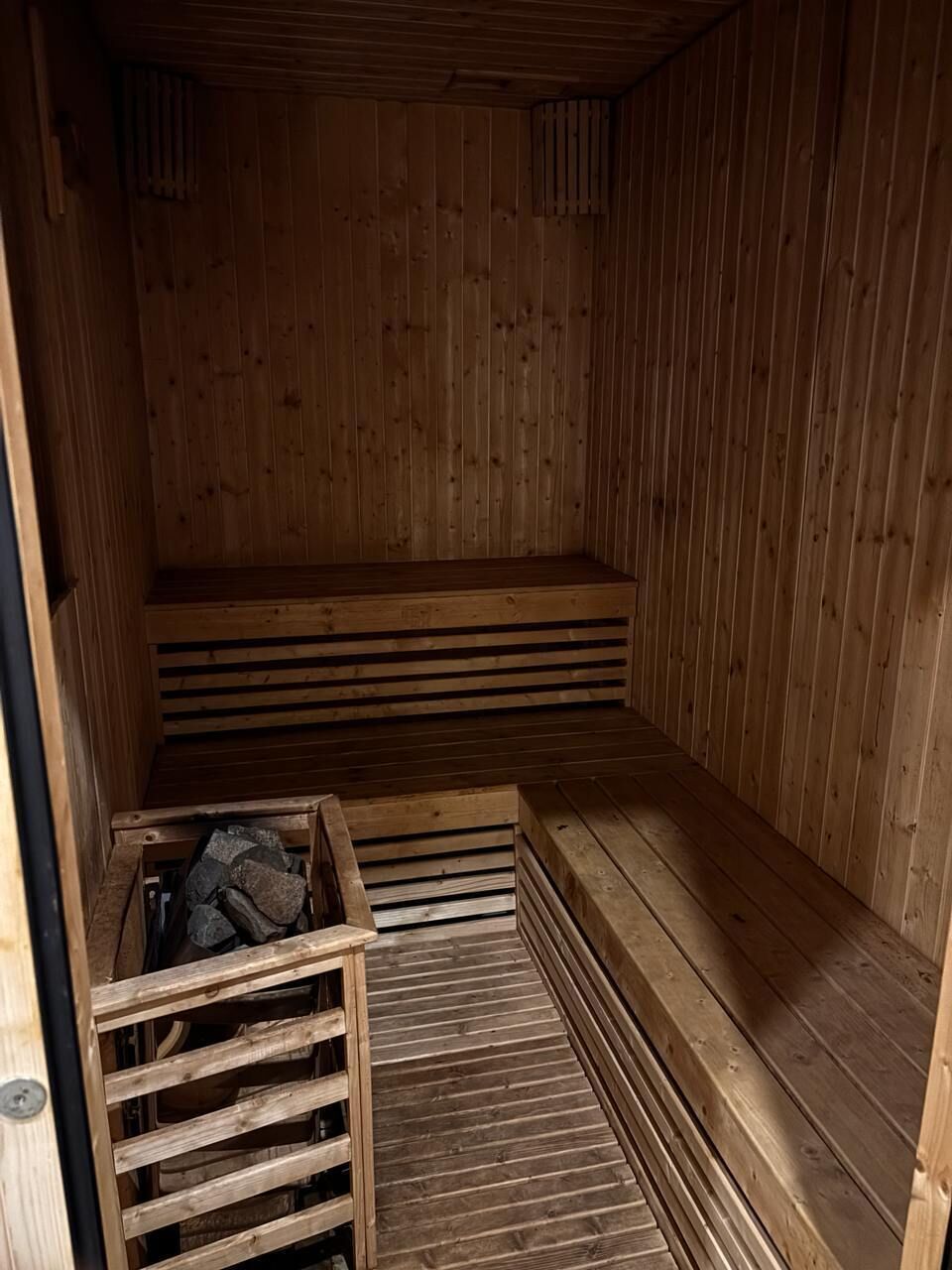 Een houten sauna met banken en een bank met een opbergvak.