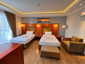 A hotel room with two beds, a desk, a chair, and a painting on the wall. - 2RN Solomon Hotel (Sendafa)