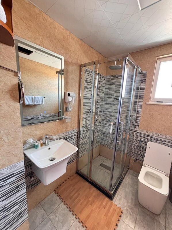 Une salle de bain moderne avec une douche à parois de verre, un lavabo et des toilettes.