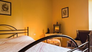 Un dormitorio con una cama, una silla, un escritorio y dos cuadros en la pared.