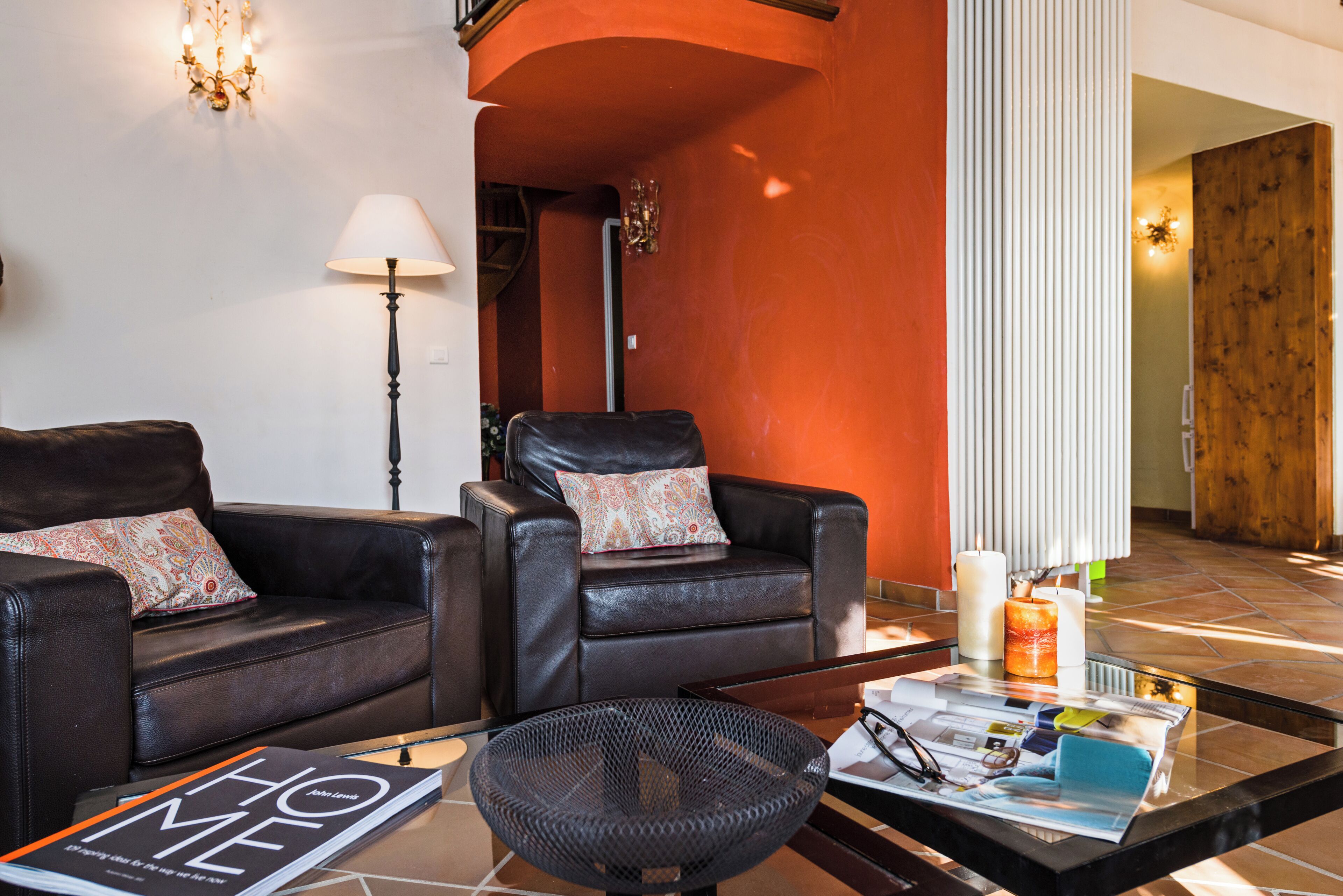 A modern living room with leather sofas, a glass coffee table, and a magazine.