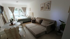 A modern living room with a sofa, a dining table, and a bed. - Beautiful Studio Apartment in Green Park II, Solanas (Maldonado)