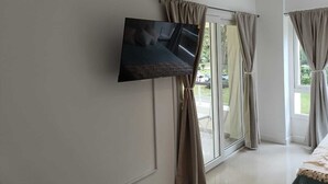 A room with a television mounted on the wall, a sliding glass door, and curtains. - Beautiful Studio Apartment in Green Park II, Solanas (Maldonado)