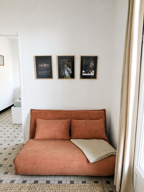Ein Zimmer mit einem braunen Sofa, einem kleinen weißen Tisch und drei gerahmten Bildern an der Wand.