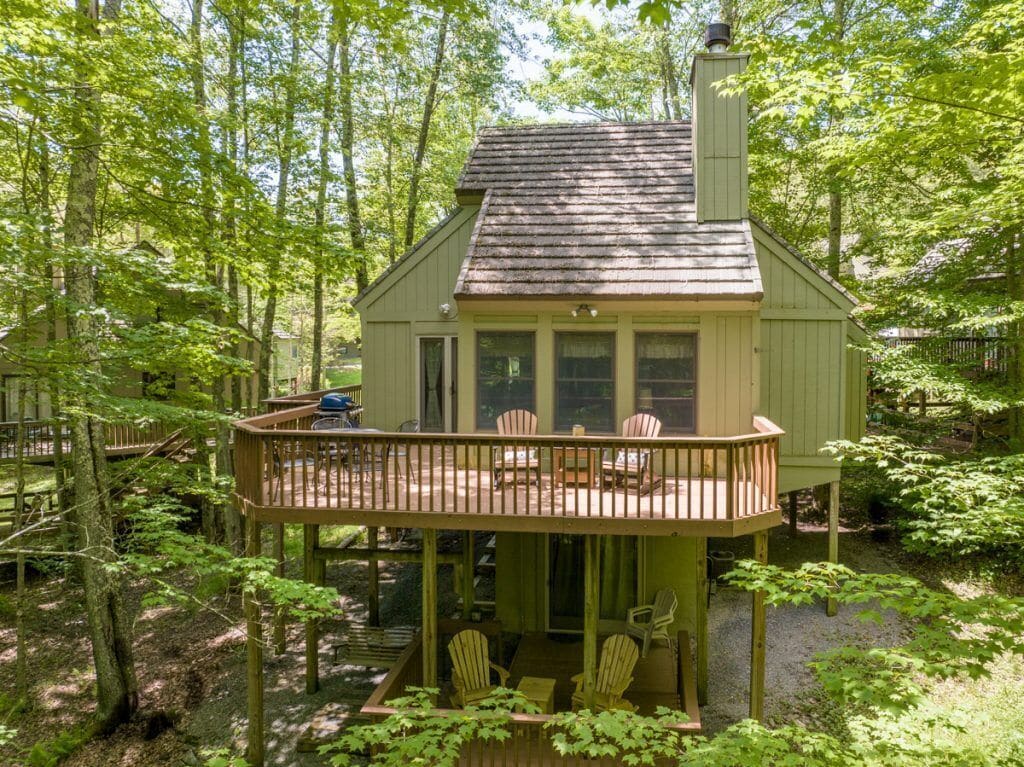 A cabin with a deck, surrounded by trees.