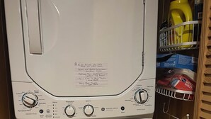 A front view of a white washing machine with a control panel, a step stool, and a shelf with laundry supplies. - Cozy cabin in Davis, WV 
Hibernation Station - Black Bear Resort (Davis)