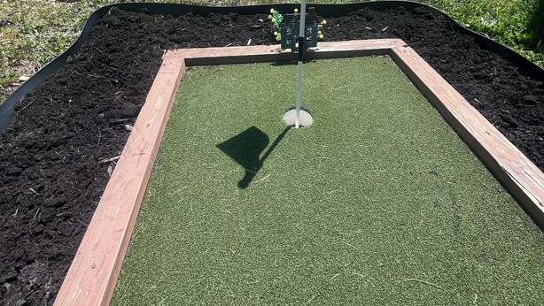 A miniature golf course with a flagstick in the center, surrounded by a green artificial turf and bordered by a brick edge. - Cozy cabin in Davis, WV 
Hibernation Station - Black Bear Resort (Davis)