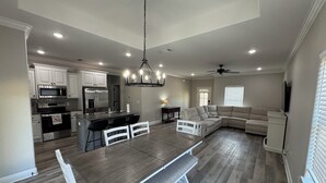 A modern kitchen with stainless steel appliances, a dining area with a bench, and a living room with a sectional sofa. - 3-bedroom house in Ruston near LA Tech & Ruston Sports Complex (Ruston)