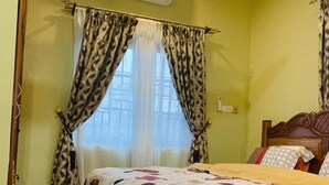 Een slaapkamer met een bed, gordijnen, een airconditioning en een betegelde vloer.