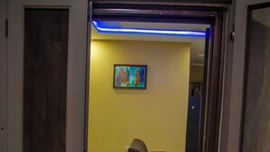 Een open deur die leidt naar een woonruimte met een bank en een schilderij aan de muur.