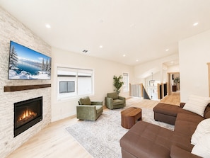 A spacious living room with a fireplace, a large TV, and a cozy seating area.
