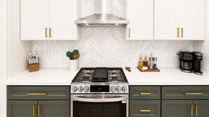 A kitchen with white cabinets, a stainless steel range hood, a gas stove, and a coffee maker. - South Lake Tahoe Home Near Heavenly, Edgewood Golf & beaches (SLT1040) (South Lake Tahoe)