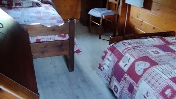 Une cabine équipée de deux lits, d’une chaise, d’une table et d’une fenêtre.