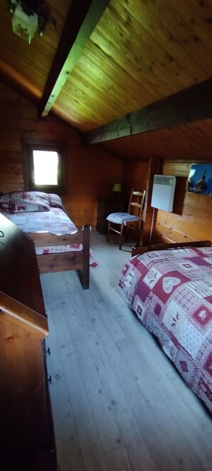 A cabin with two beds, a chair, a table, and a window. - The Cabrette Chalet, for 8 to 10 people—perfect for families (La Rivière-Enverse)