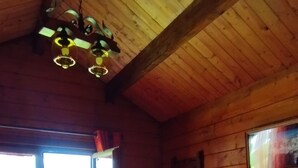 Une pièce de cabane en bois comprenant un lit, une commode et un luminaire suspendu.