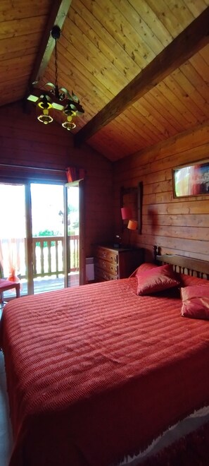 A wooden cabin room with a bed, a dresser, and a hanging light fixture. - The Cabrette Chalet, for 8 to 10 people—perfect for families (La Rivière-Enverse)