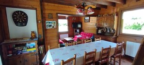 A wooden interior with a dartboard, a table with chairs, a red sofa, and a television. - The Cabrette Chalet, for 8 to 10 people—perfect for families (La Rivière-Enverse)