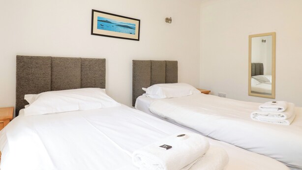 Habitación de hotel con dos camas, un cuadro en la pared, un espejo y una cama bien hecha con toallas.