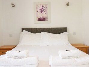 A hotel room with a bed, two bedside tables, and a painting on the wall. - 62 Golf Lodges (St. Columb Major)