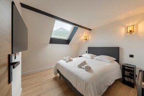 Ein Schlafzimmer mit einem Bett, einem Oberlicht, einem Fernseher und einem Nachttisch.