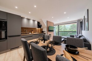 A modern kitchen with dark cabinets, a wooden countertop, and a built-in oven. - Suite Myrtilles - Bel appartement moderne pour 4 (Saint-Chaffrey)