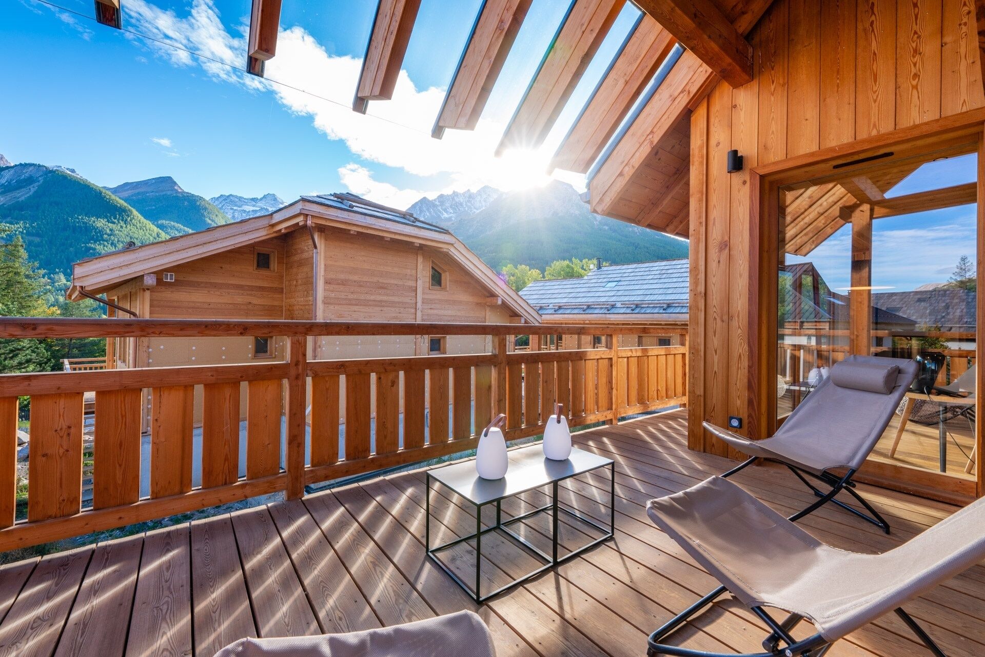 A wooden deck with a table and chairs, overlooking a mountain landscape.