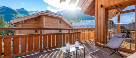 A wooden deck with a table and chairs, overlooking a mountain landscape.