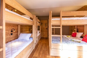 A room with bunk beds, wooden walls, and a door. - Malago - Five Bedroom Chalet, Sleeps 14 (Le Monêtier-les-Bains)