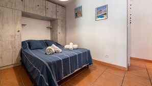 A bedroom with a bed, a wardrobe, and two framed pictures on the wall. - Le Cocody - Appt avec terrasse, proche de la plage (Lumio)