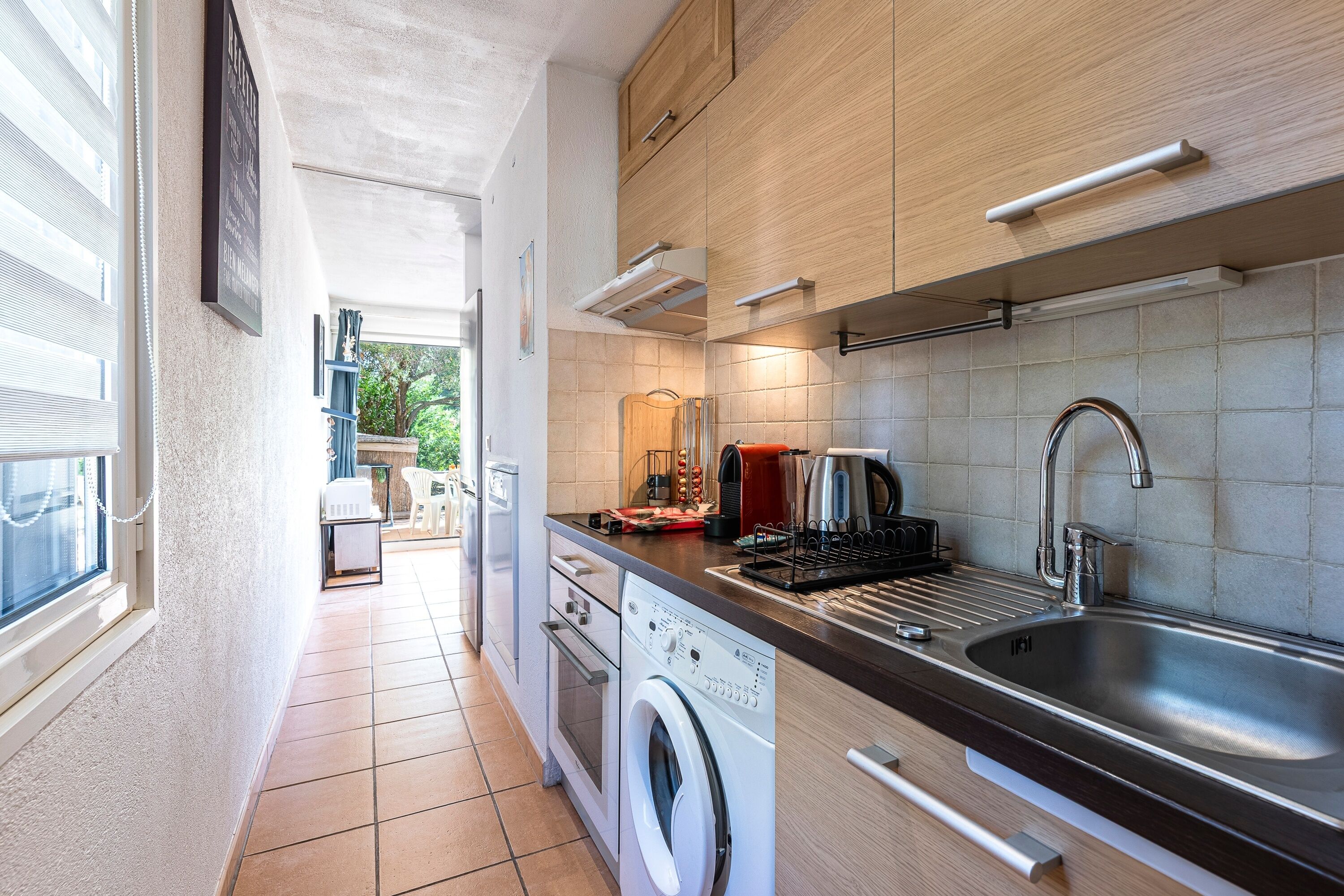A compact kitchen with a washing machine, a sink, and a coffee maker.