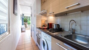 A compact kitchen with a washing machine, a sink, and a coffee maker. - Le Cocody - Appt avec terrasse, proche de la plage (Lumio)