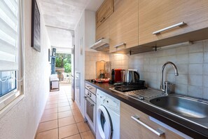 A compact kitchen with a washing machine, a sink, and a coffee maker. - Le Cocody - Appt avec terrasse, proche de la plage (Lumio)