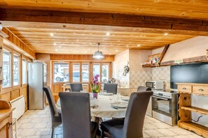 Un interior de madera con una mesa de comedor, sillas, un refrigerador y una zona de cocina con microondas y horno.