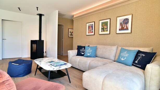 A living room with a sofa, a coffee table, a blue bean bag, and a fireplace. - Ker Siméon - Maison moderne à 600 m de la plage (Saint-Cast-le-Guildo)