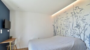 A bedroom with a bed, a desk, a chair, and a wall-mounted TV. - Ker Siméon - Maison moderne à 600 m de la plage (Saint-Cast-le-Guildo)