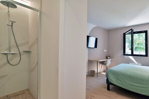 A modern bathroom with a shower, a bed, a desk, and a TV. - Ker Siméon - Maison moderne à 600 m de la plage (Saint-Cast-le-Guildo)