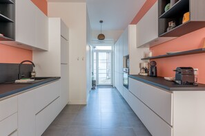 A modern kitchen with white cabinetry, a black countertop, and a view to the outside. - Châteaubriand - Appt pour 4 au cœur de Nantes (Nantes)