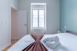 Ein Schlafzimmer mit Bett, Fenster, Tür und Nachttischlampe.