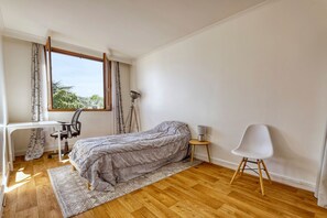 Ein Schlafzimmer mit Bett, Schreibtisch, Stuhl und Lampe.