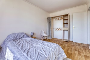 A bedroom with a bed, a chair, a wardrobe, and a small table. - Louis Choix - À 1 km de la gare Garges (Garges-les-Gonesse)