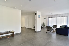 Un vaste espace de vie comprenant un canapé bleu, un banc en bois et une table à manger avec des chaises.