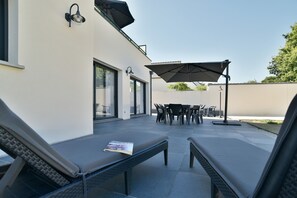 An outdoor patio area with lounge chairs, a table, and umbrellas.