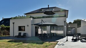 A modern two-story house with a patio, outdoor seating, and a covered area. - Ti Kastrilhez - 1er - À 1 km de la plage (Saint-Cast-le-Guildo)